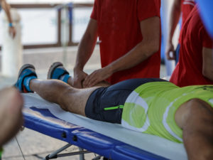 Athlete lying on a Bed while having Legs Massaged after a Physical Sports Workout.
