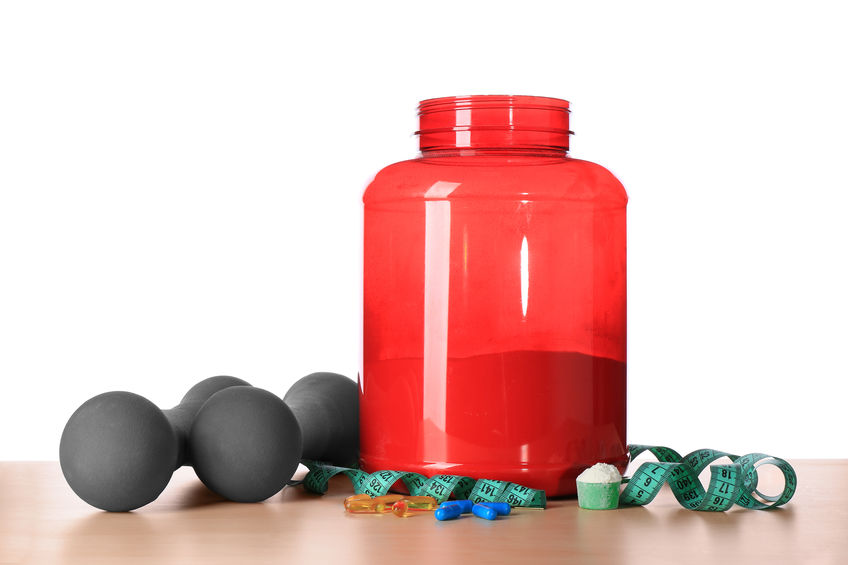 Protein powder, pills, dumbbells and measuring tape on table