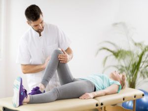 Middle age woman with knee injury lying on physiotherapy