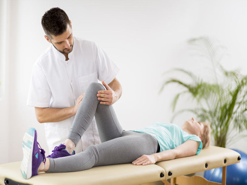 Middle age woman with knee injury lying on physiotherapy 