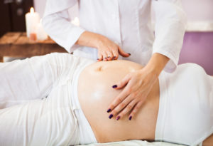 Young pregnant woman having abdominal massage