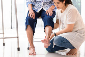 Asian young woman checking knee of elderly woman at home