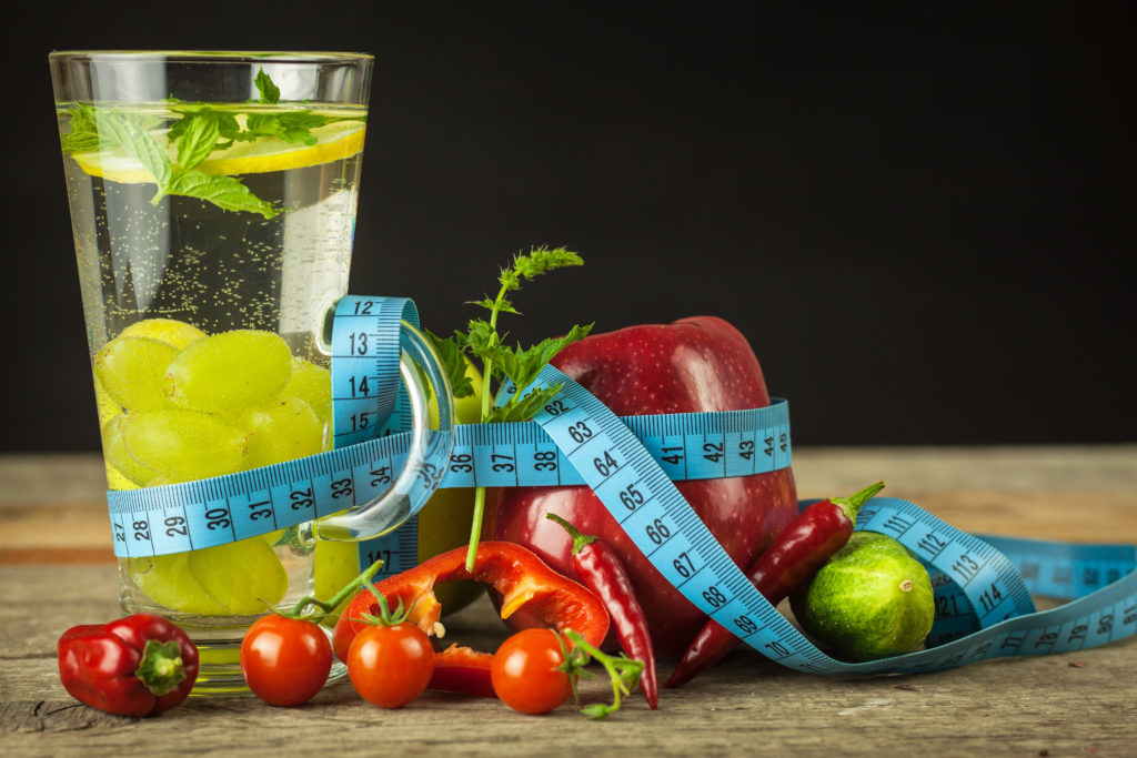 Glasses of water and a tailor's meter. Fruits and vegetables. The concept of weight loss. Healthy diet.