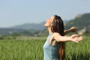 Happy woman breathing deeply fresh air in a field