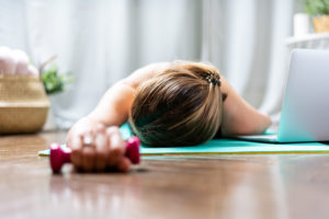 Woman falling asleep. Tired after exercise and workout. Overtraining concept. Exhausted woman lying on floor and resting after heavy cardio training in home gym at yoga mat